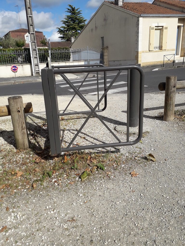 Portique métallique pivotant, en forme de fer à cheval. Deux barrières en bois de chaque côté.